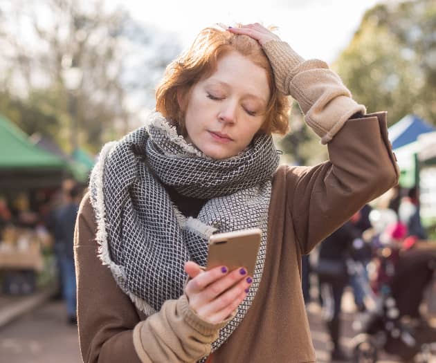 Stressed woman holding a phone with her eyes closed