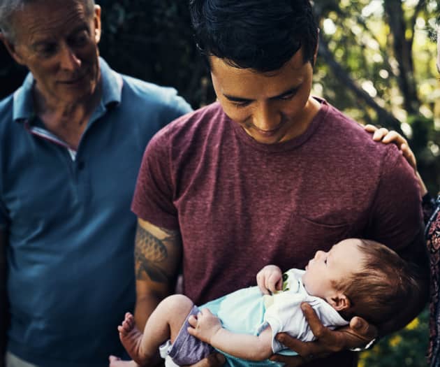 Dad holding newborn surrounded by family