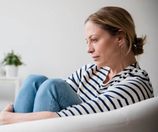 Woman sat on the sofa looking depressed