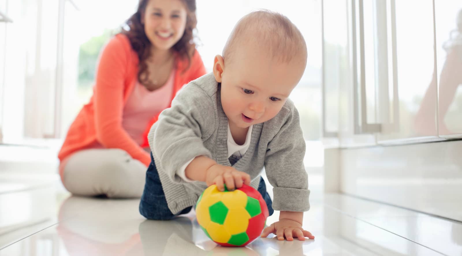 Mum watching baby play with a ball